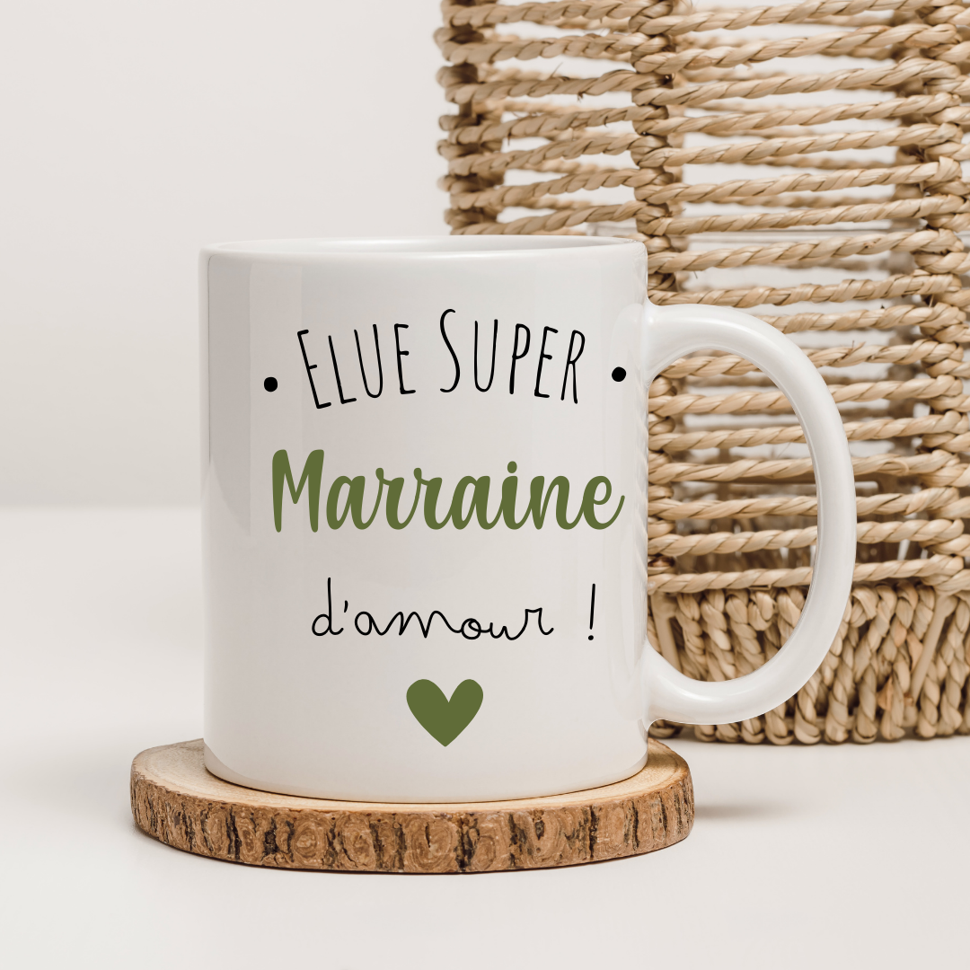 Mug "Élue Super Marraine" dans une jolie boîte cadeau entourée de rubans colorés.
