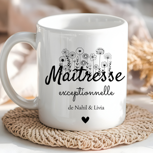  Mug blanc avec l’inscription "Maîtresse Exceptionnelle" et le prénom "Lucas" posé sur une table entourée de fournitures scolaires.